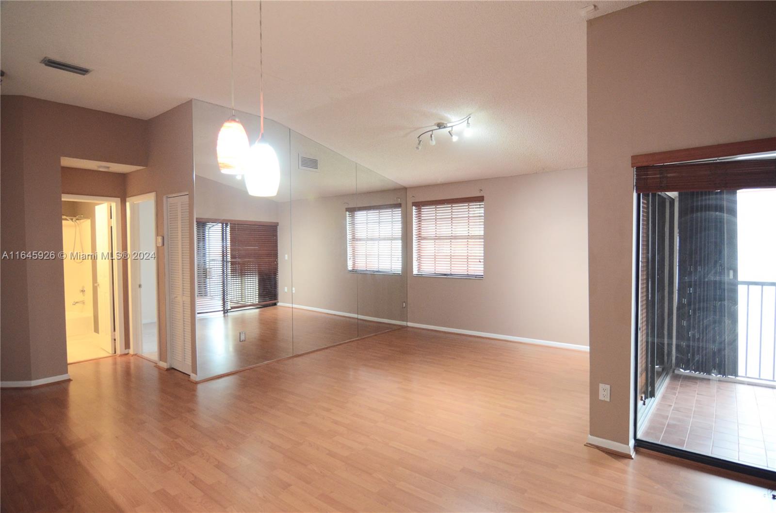 an empty room with wooden floor and windows