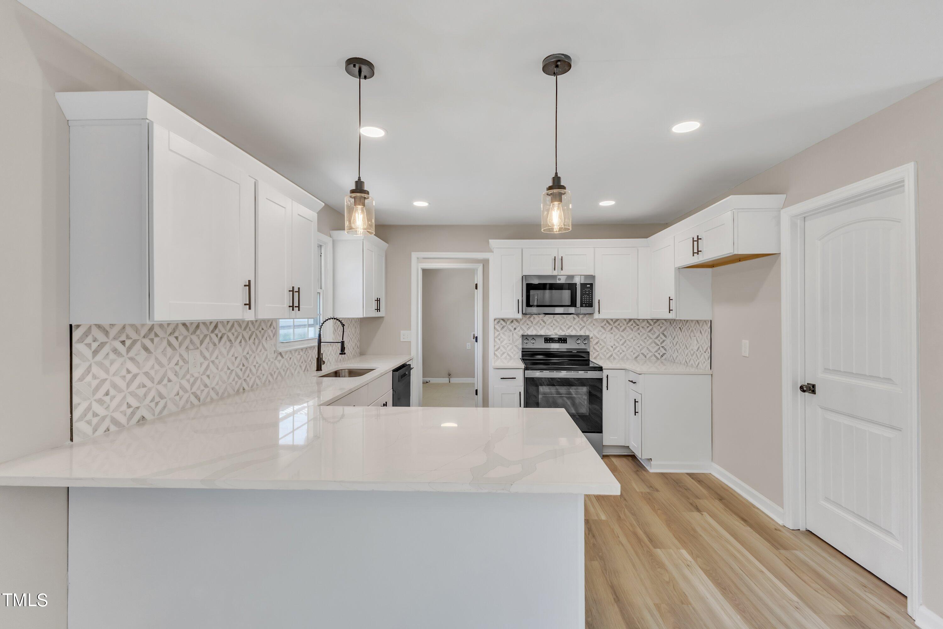 a large white kitchen with a refrigerator a stove top oven a sink and kitchen island