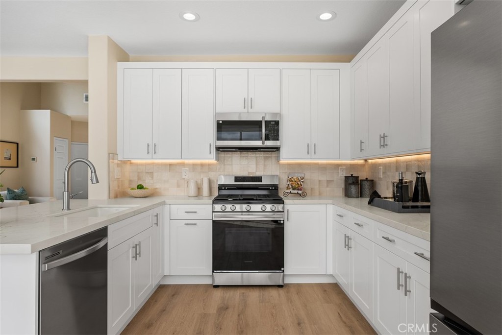 a kitchen with stainless steel appliances granite countertop a stove and white cabinets