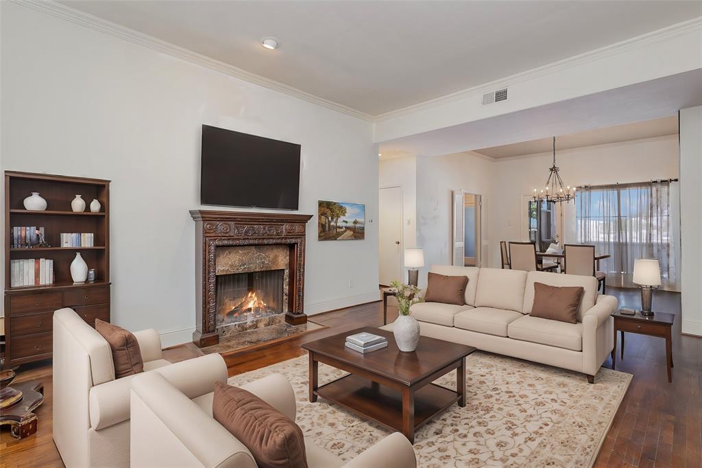 Living room with a high end fireplace, crown molding, a chandelier, and hardwood / wood-style flooring