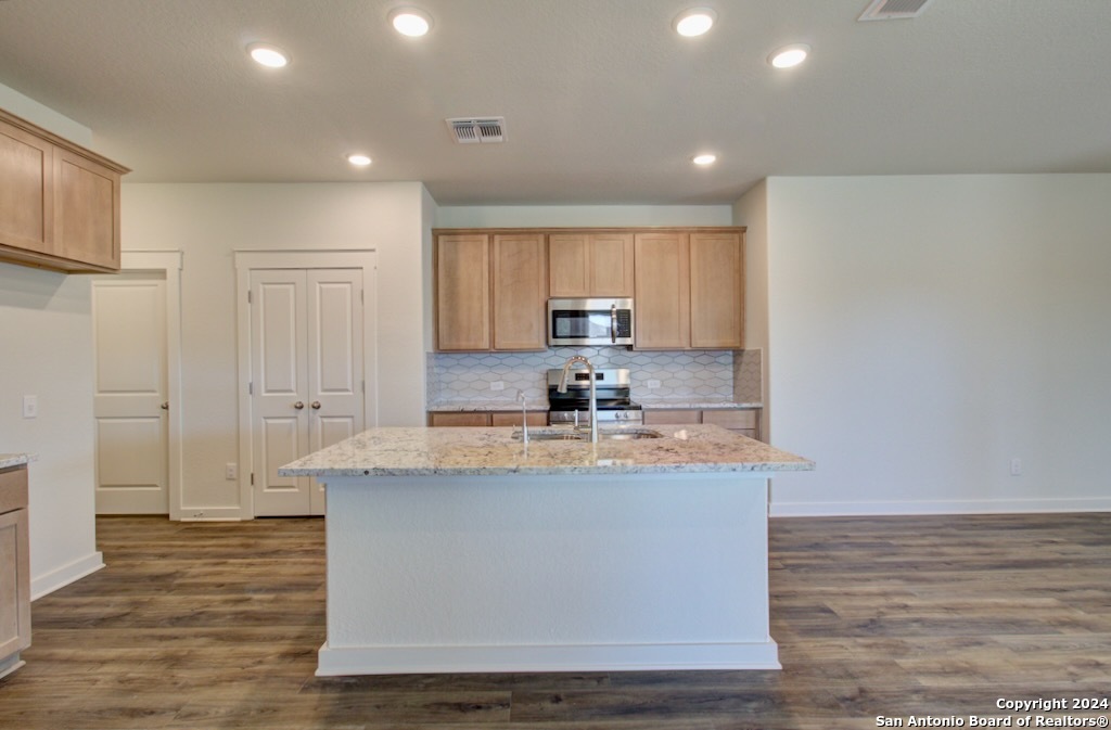 a large kitchen with granite countertop a sink and a refrigerator