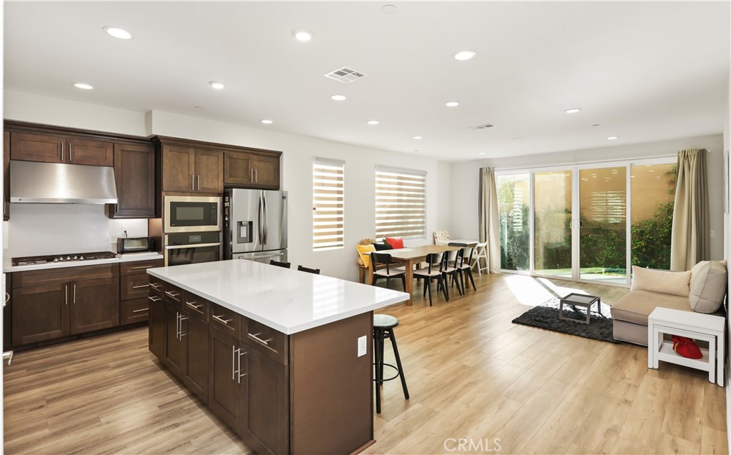 a living room with stainless steel appliances granite countertop sink stove and wooden floor