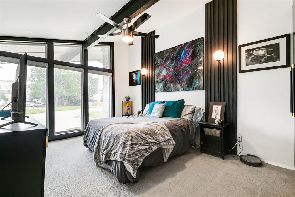 a bedroom with a bed painting on the wall and a large window