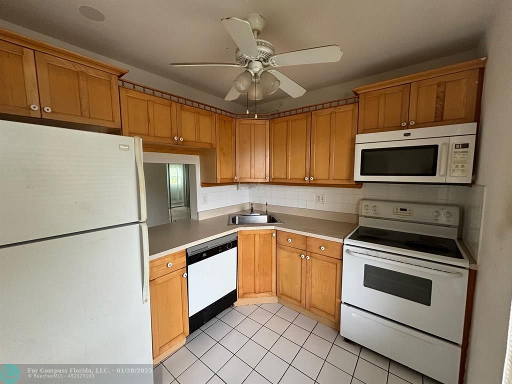 a kitchen with granite countertop a refrigerator stove and microwave