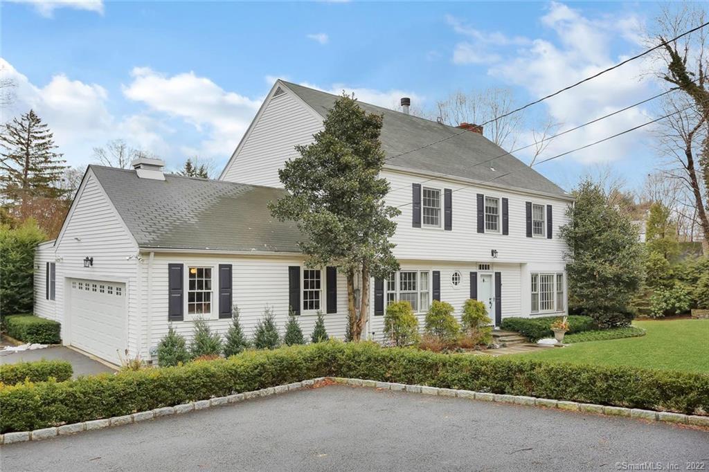 a view of a white house next to a yard and a road