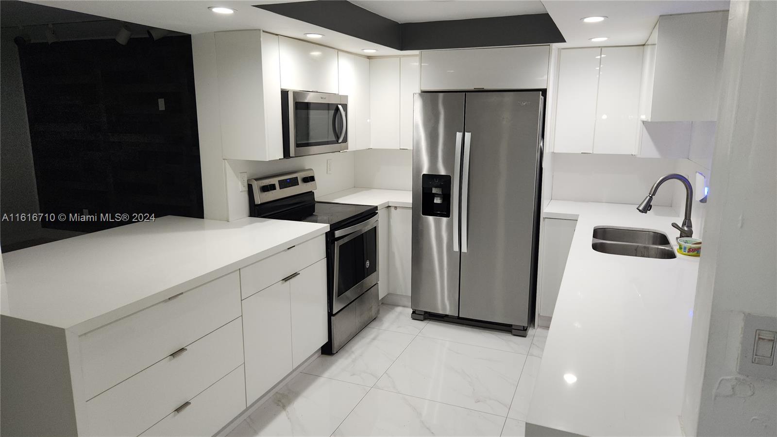 a kitchen with stainless steel appliances a refrigerator sink and microwave