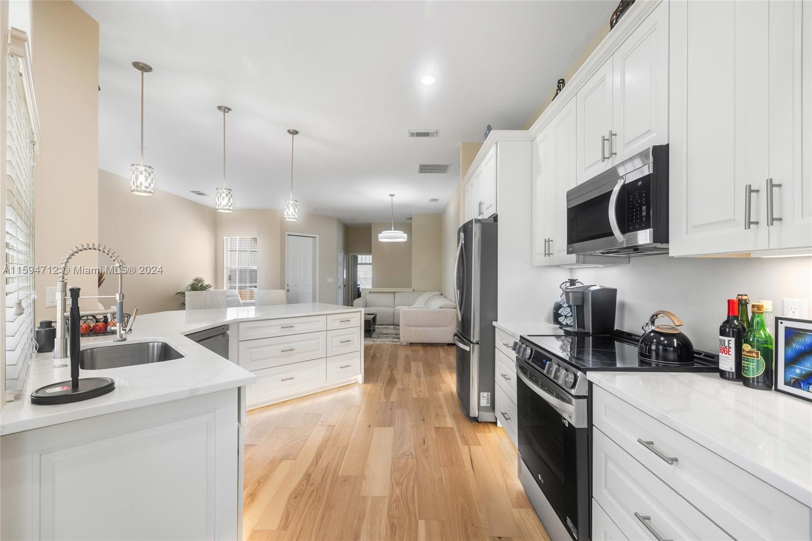 a large white kitchen with lots of counter space a sink and appliances