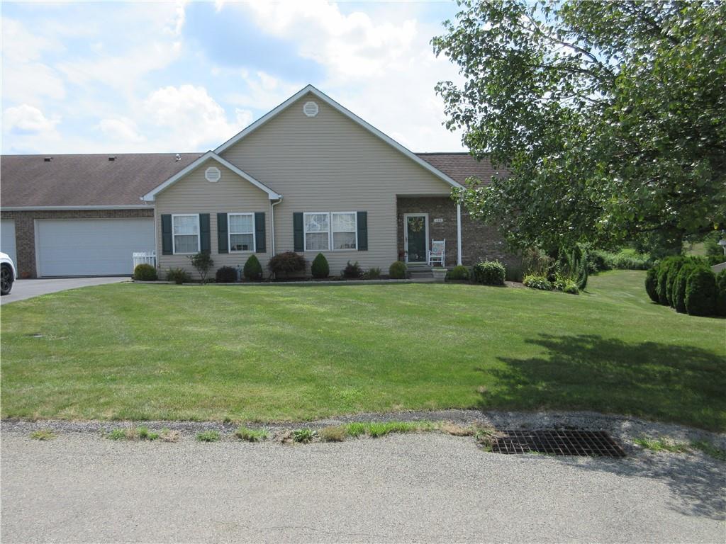 a house that is sitting in the grass with large trees and plants