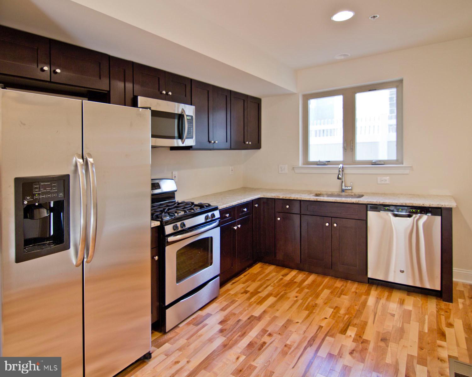 a kitchen with granite countertop a refrigerator stove and sink