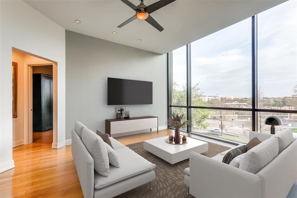 a living room with couches a coffee table and a flat screen tv with a large window with outer view