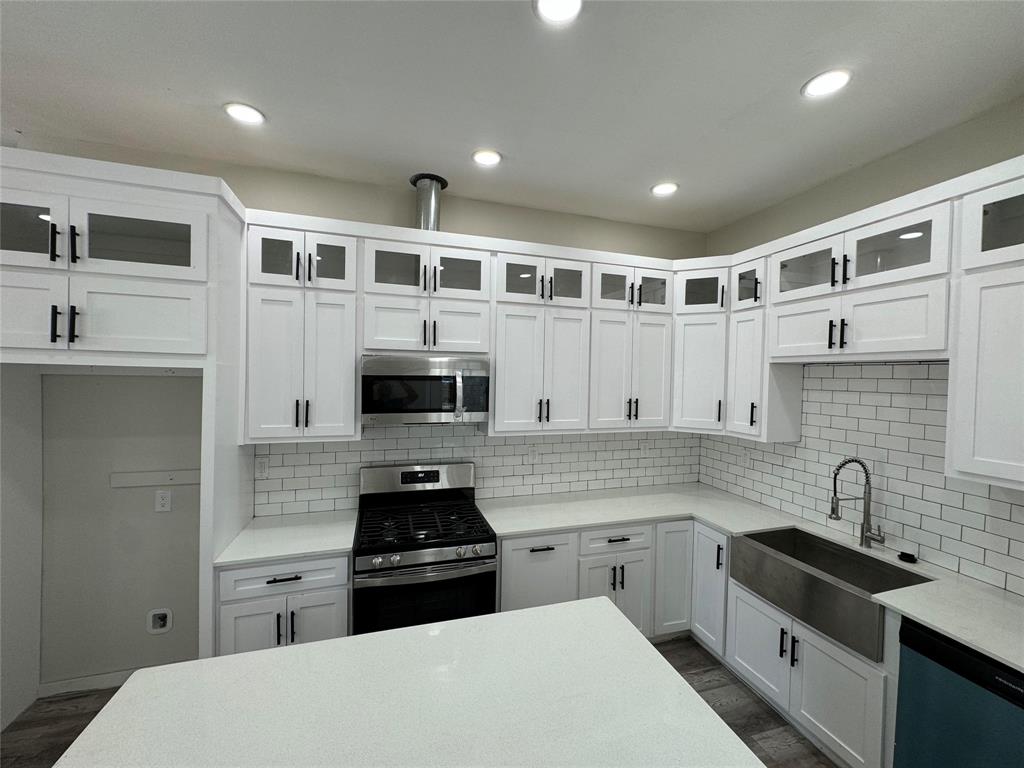 a kitchen with stainless steel appliances a stove sink microwave and cabinets