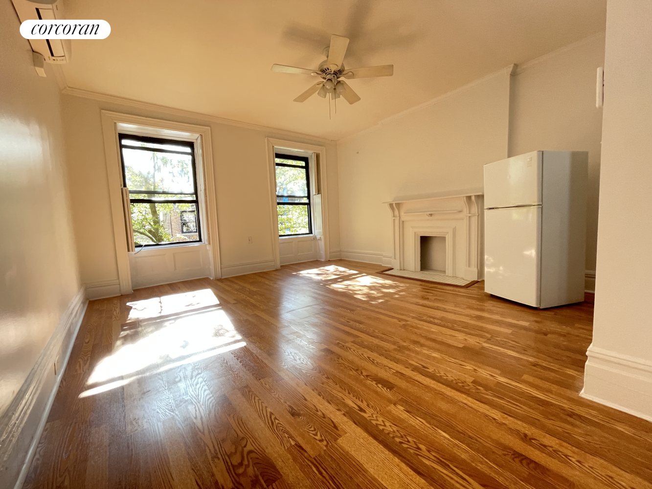 a view of an empty room with a window and wooden floor