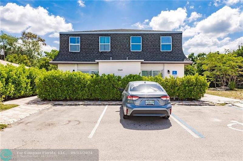 a car parked in front of a brick house with potted plants