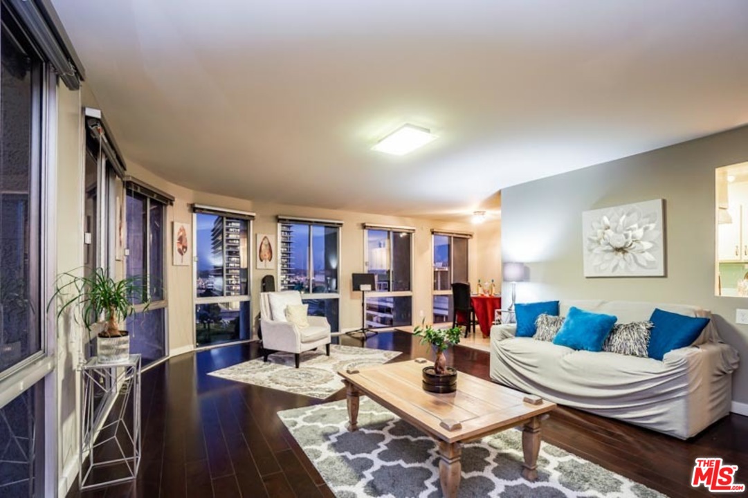 a living room with furniture kitchen view and a large window