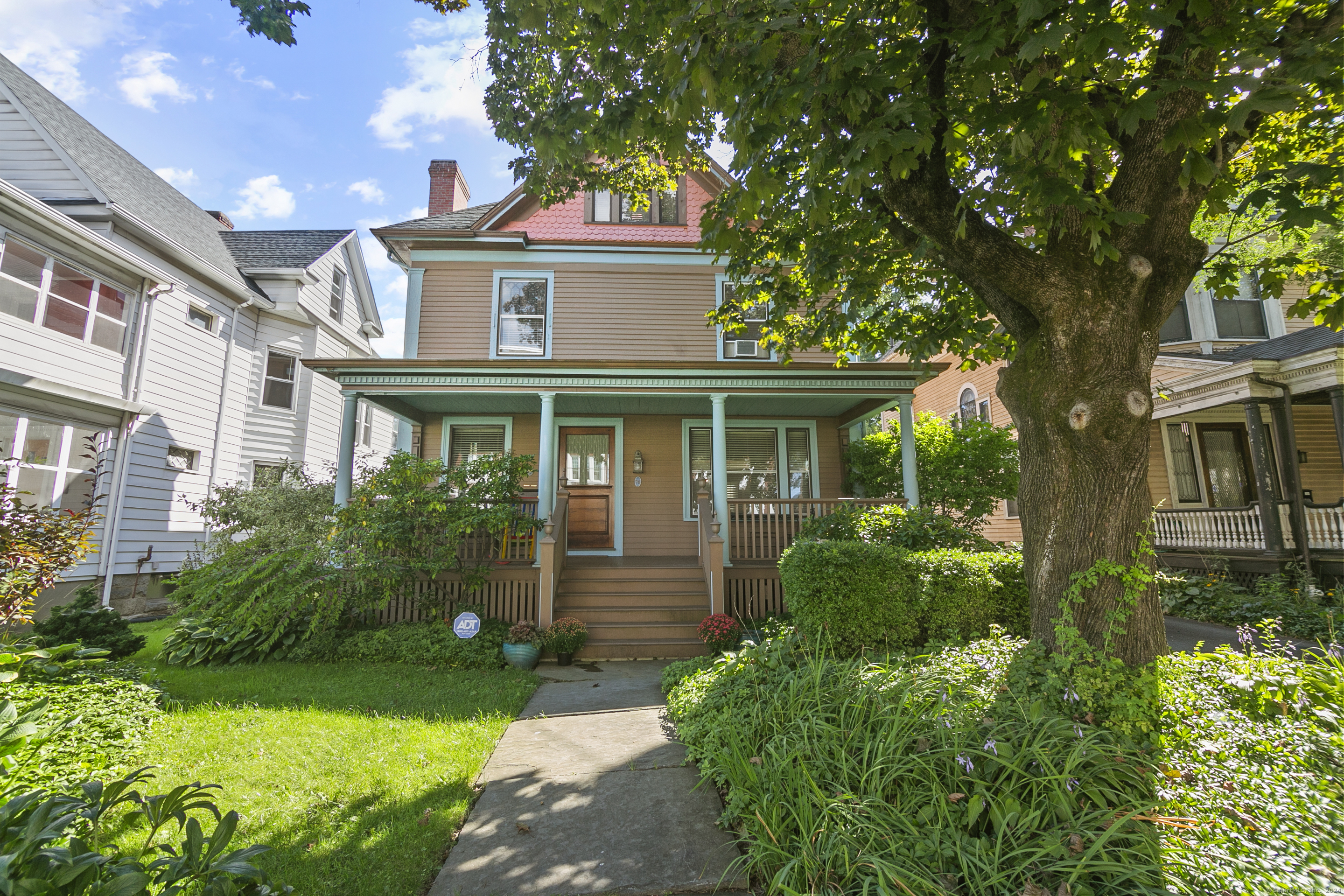 a view of a white house next to a yard with plants and trees