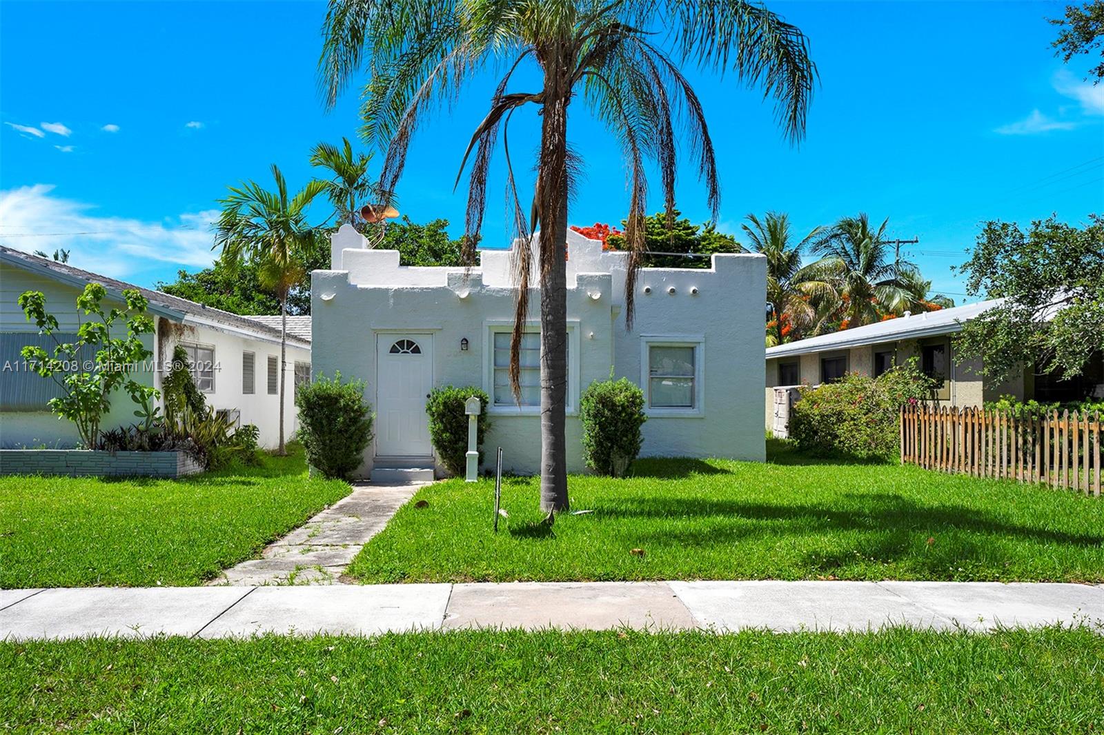 a view of a house with a yard and palm trees