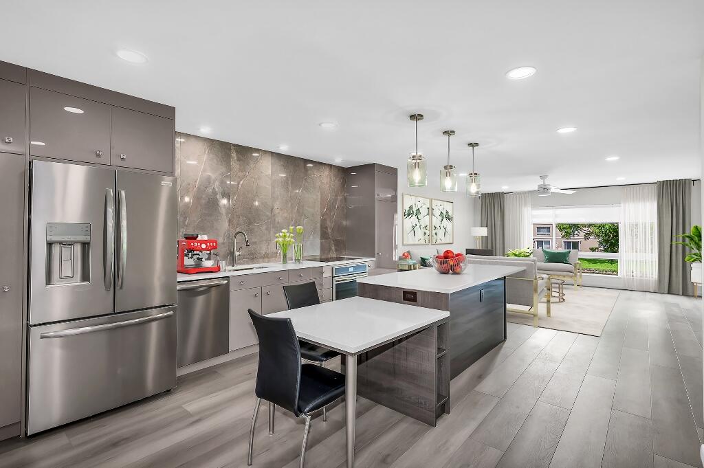 a kitchen view with stainless steel appliances kitchen island hardwood floor and a refrigerator