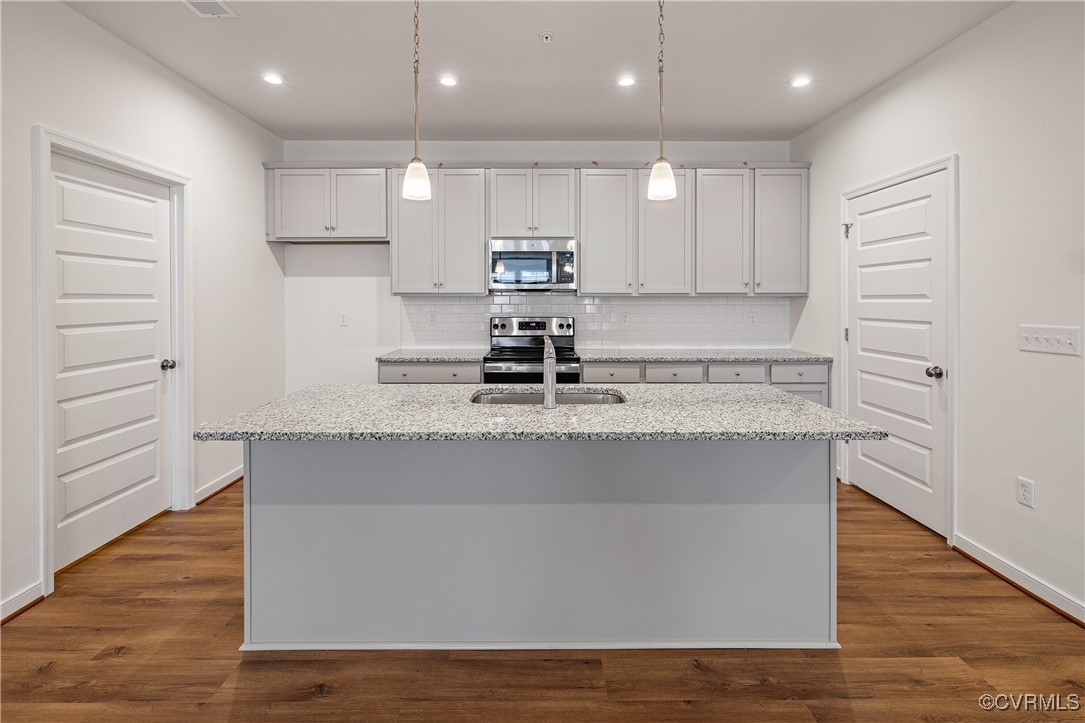 a view of kitchen with stainless steel appliances granite countertop wooden floors and view living room