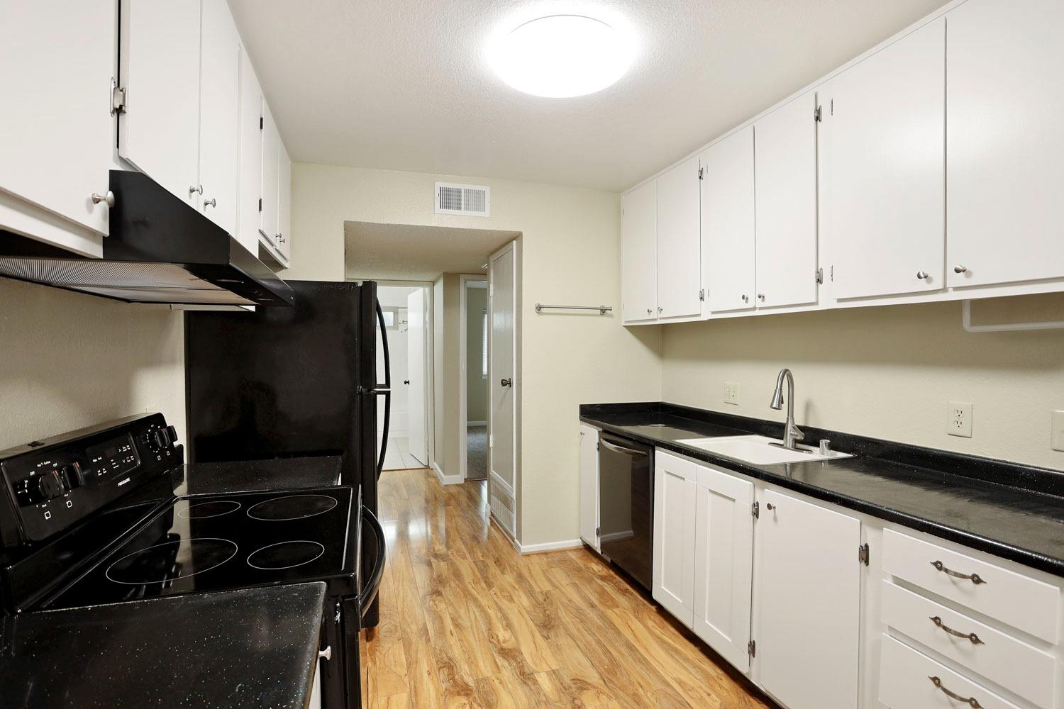 a kitchen with granite countertop a sink stove and cabinets