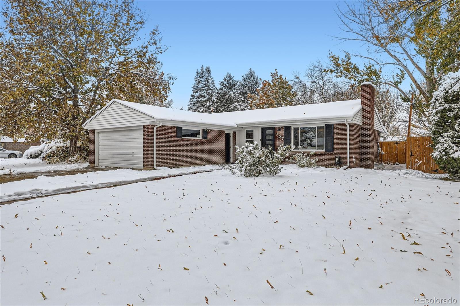 a front view of a house with a yard covered with snow