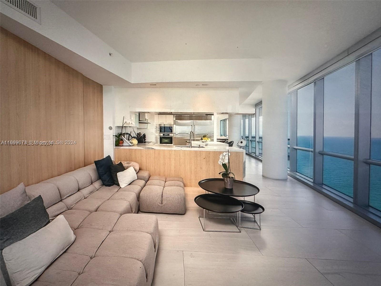 a living room with furniture a rug and kitchen view