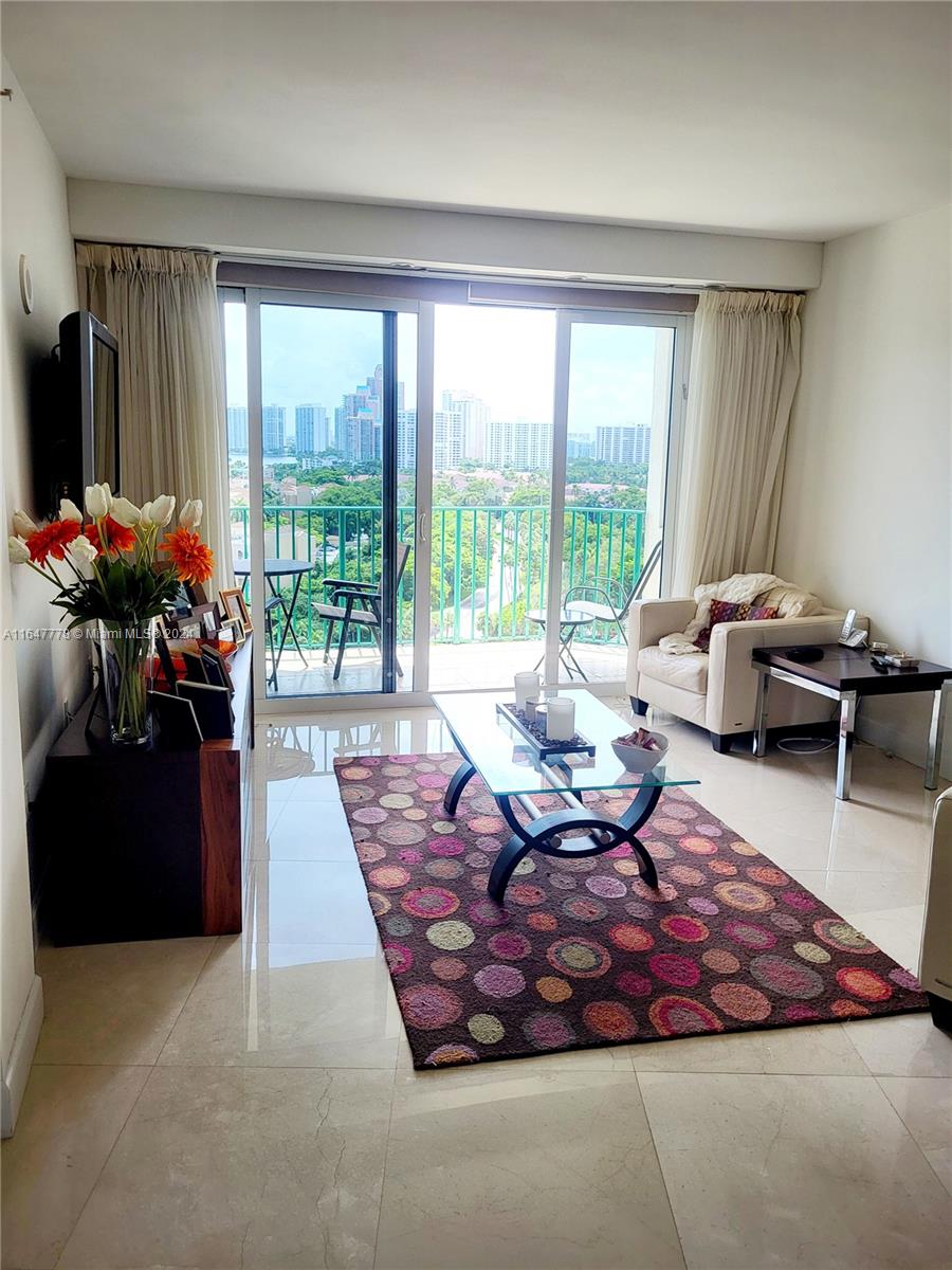 a living room with furniture floor to ceiling window and a flat screen tv