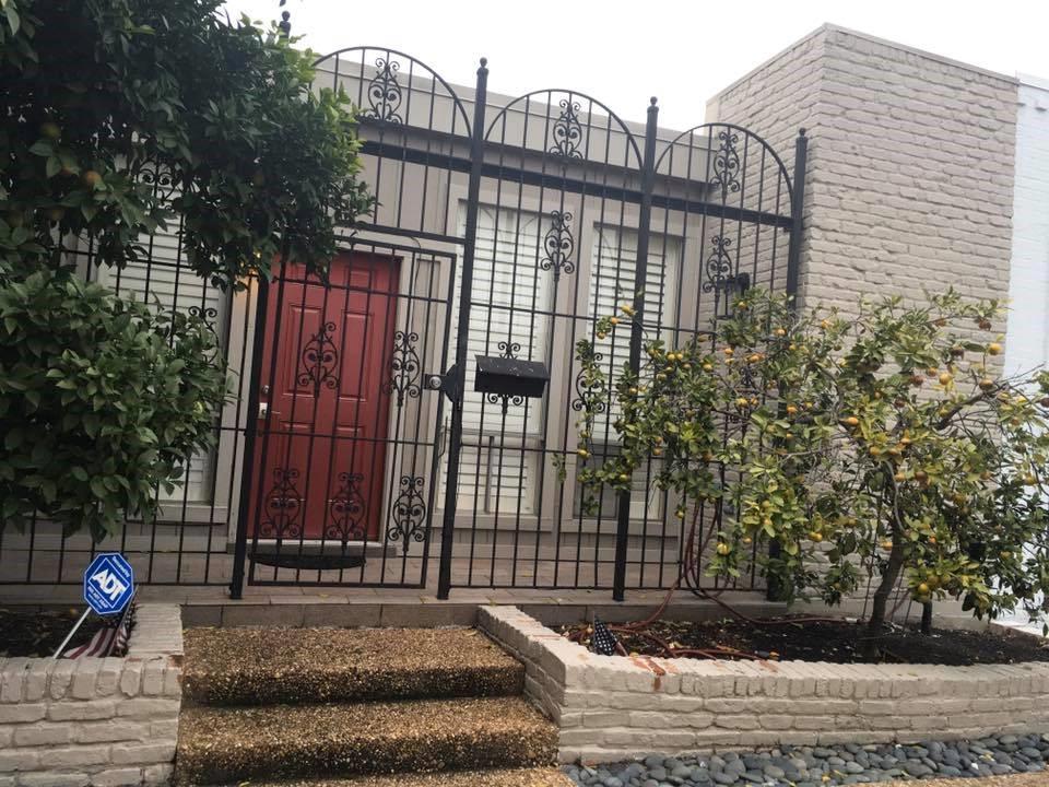 a view of a brick house with plants and wooden fence