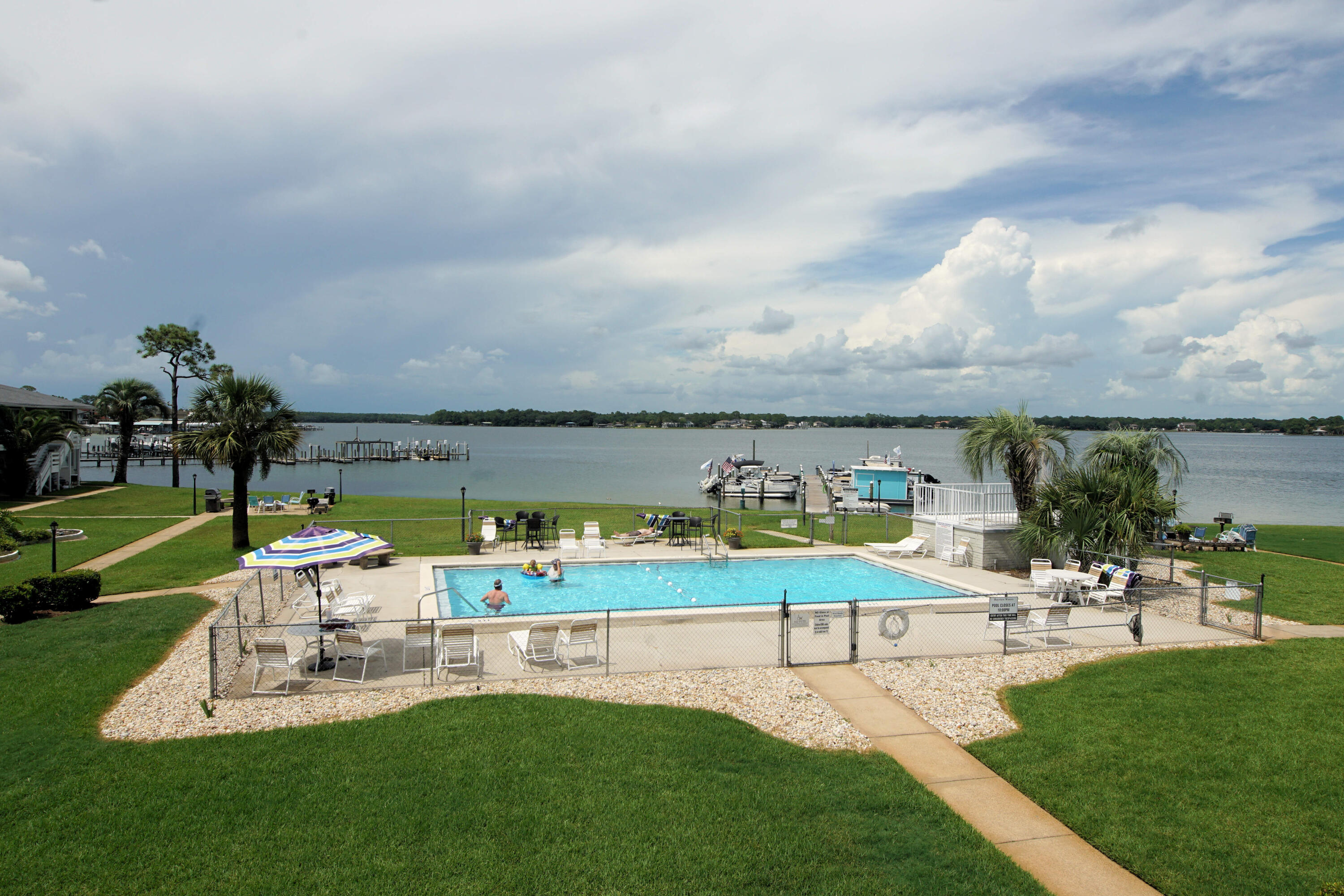 a view of a swimming pool with lawn chairs and a big yard