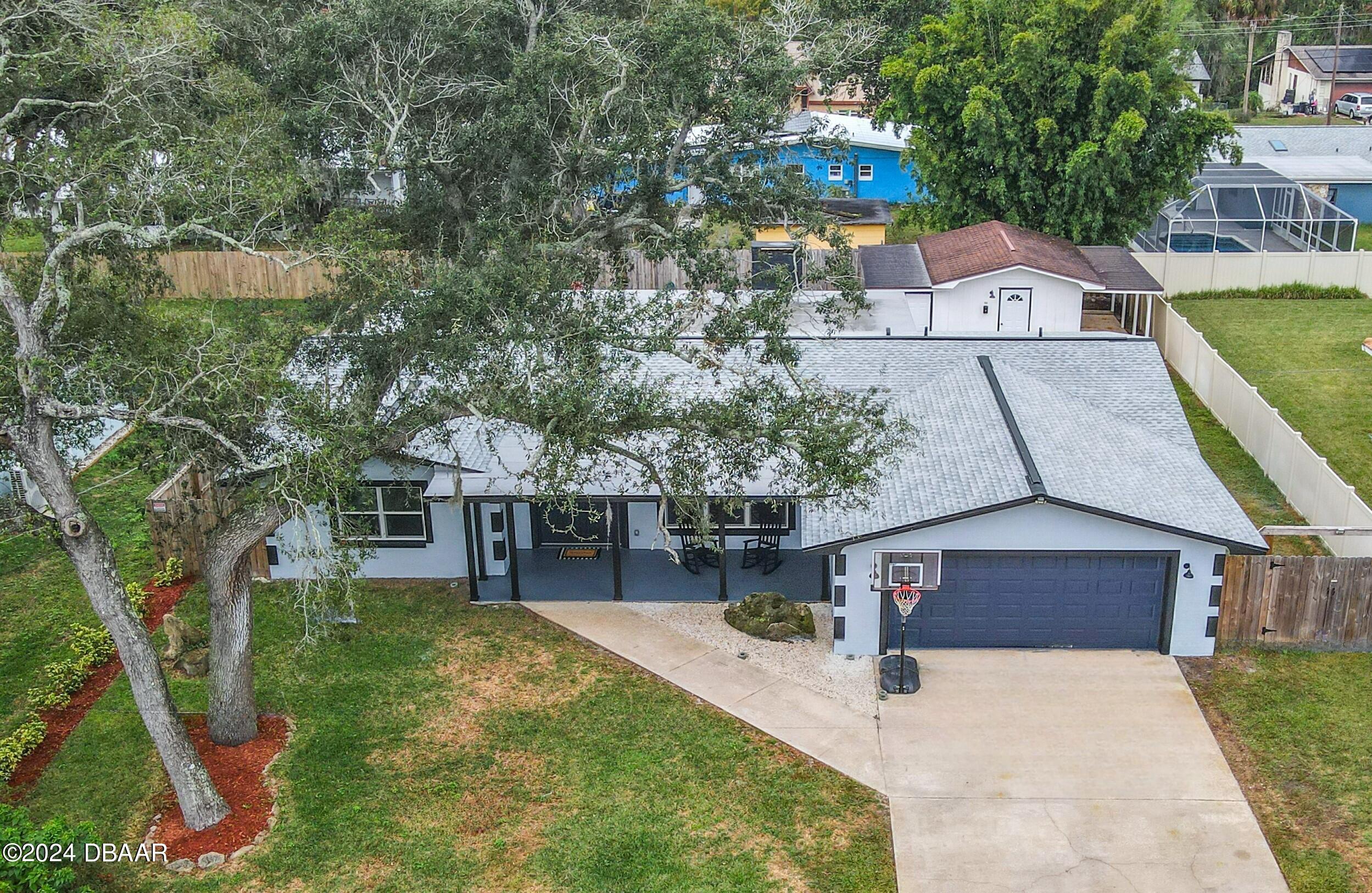 an aerial view of a house with swimming pool and large trees