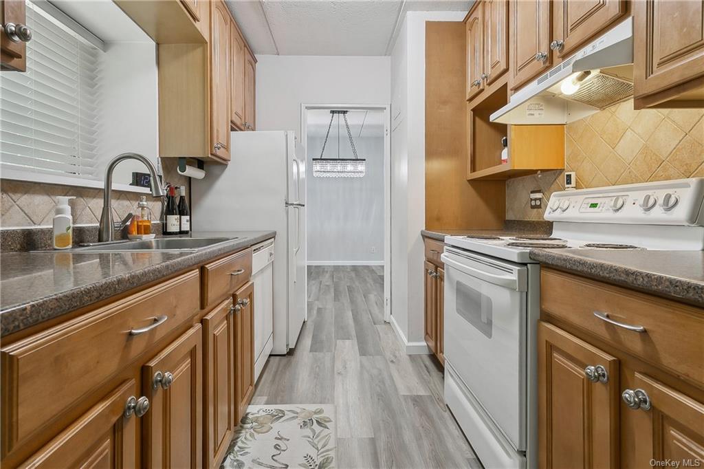 Kitchen with sink, backsplash, light hardwood / wood-style floors, and white electric range oven