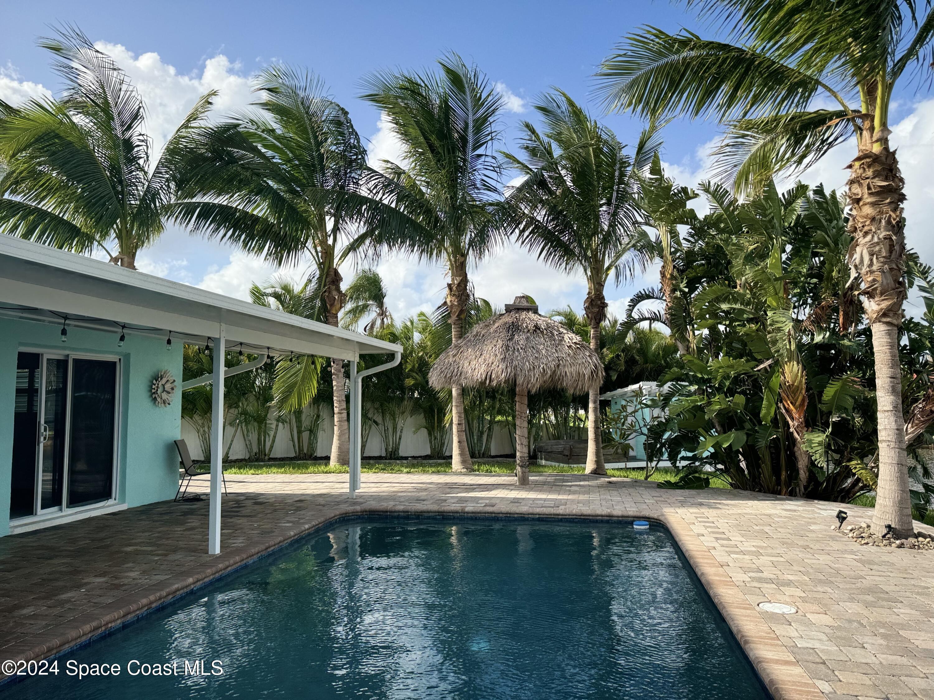 a front view of a house with swimming pool and porch with furniture