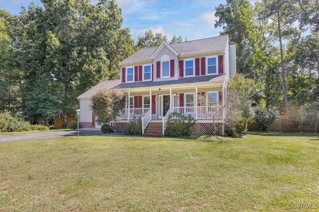 Colonial inspired home with a front lawn and cover