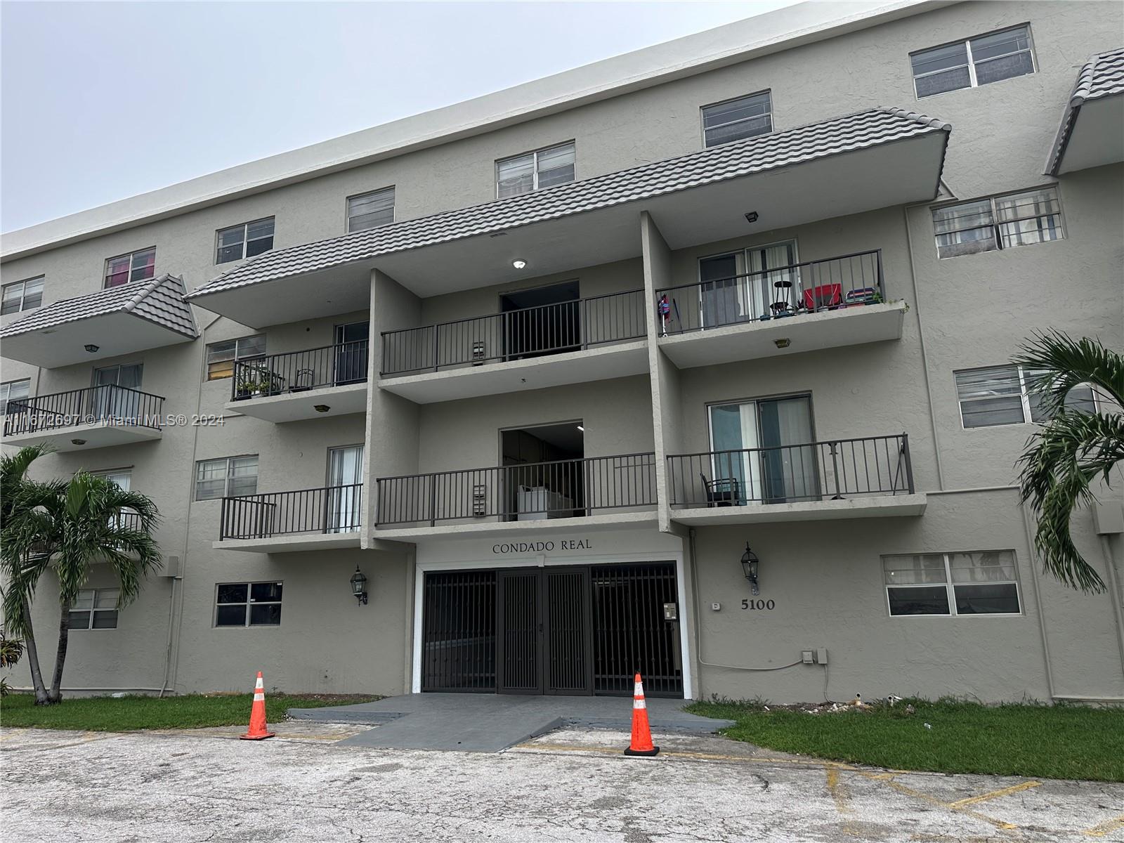 a front view of a building with a yard and parking space