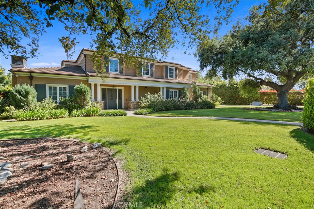 a front view of a house with garden and trees