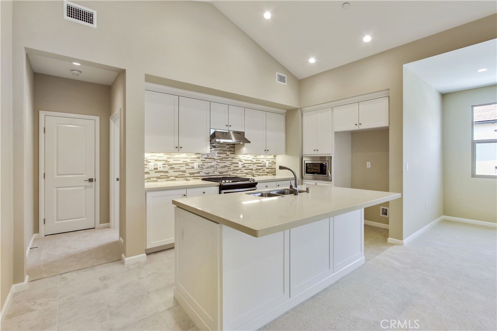 a kitchen with a sink a stove a refrigerator and white cabinets