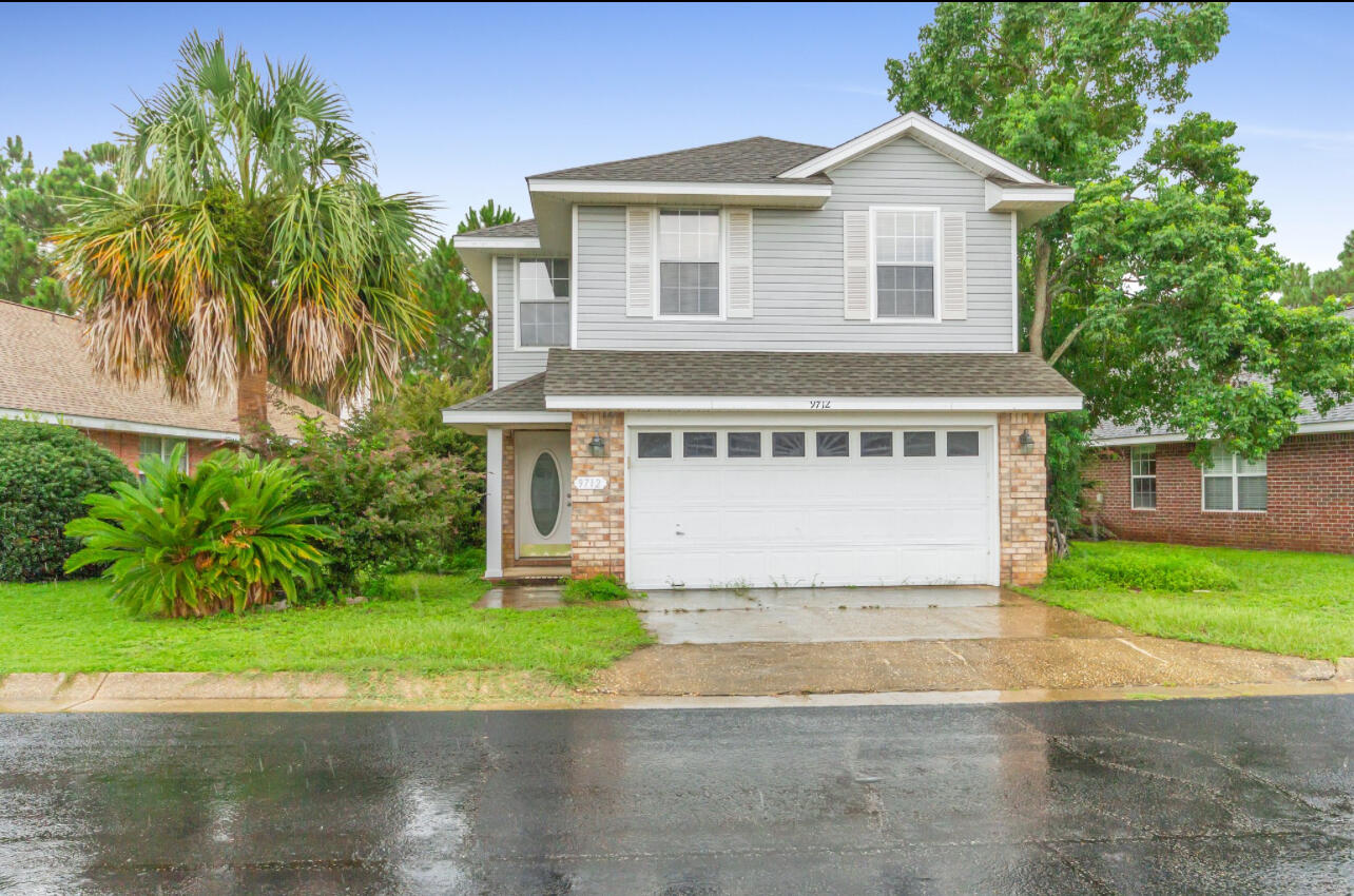 a front view of a house with a garden and tree