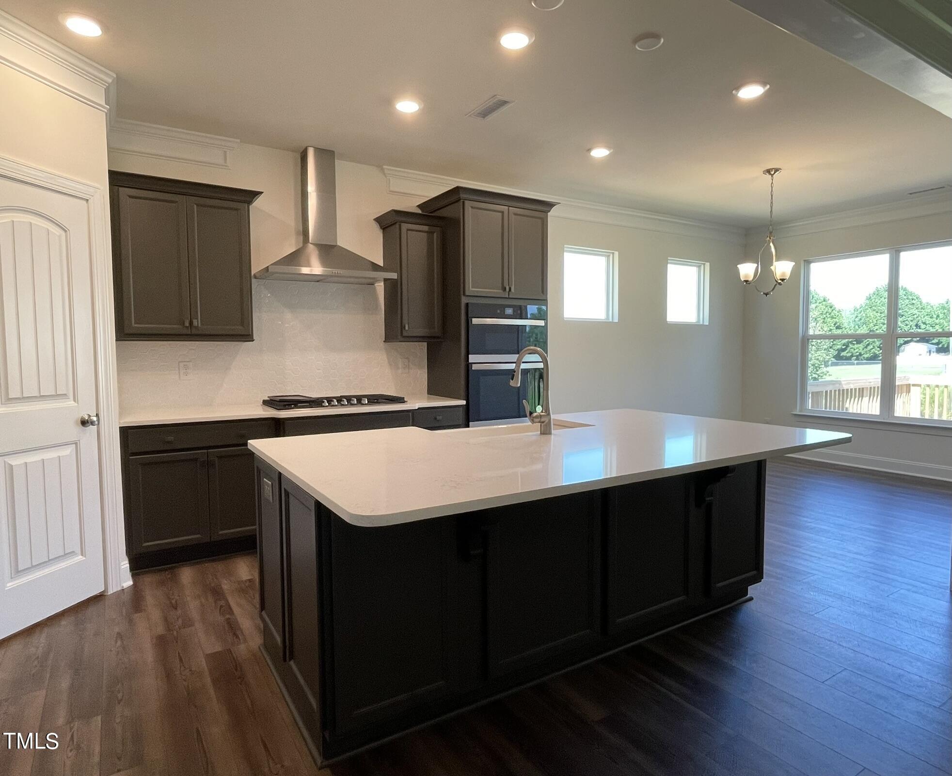 a kitchen with stainless steel appliances granite countertop a sink a stove and a wooden floors