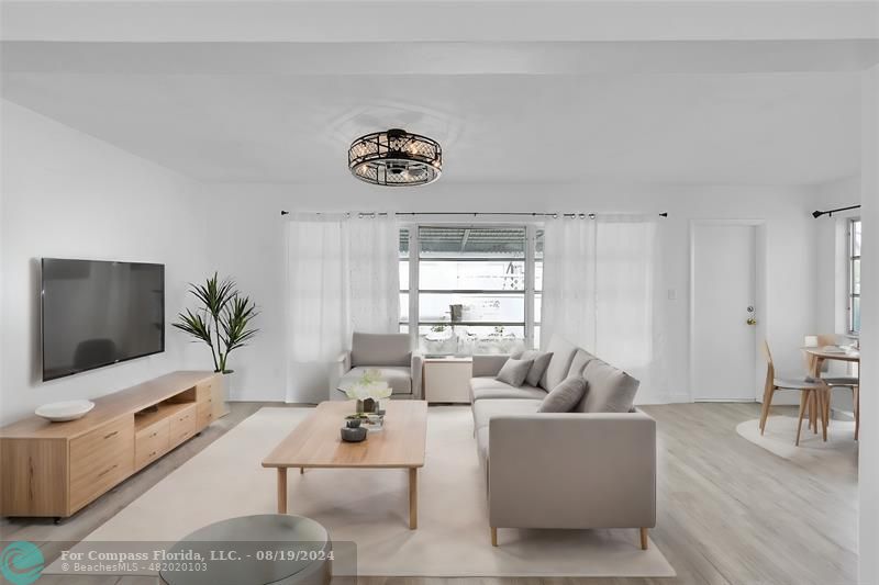 a living room with furniture a flat screen tv and a large window