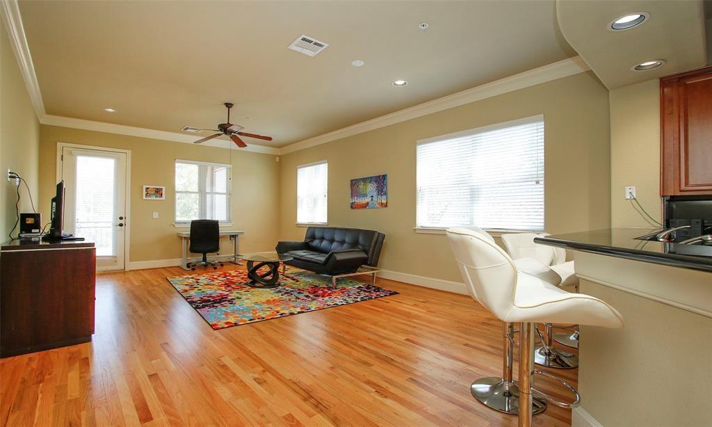 a living room with furniture a large window and wooden floor