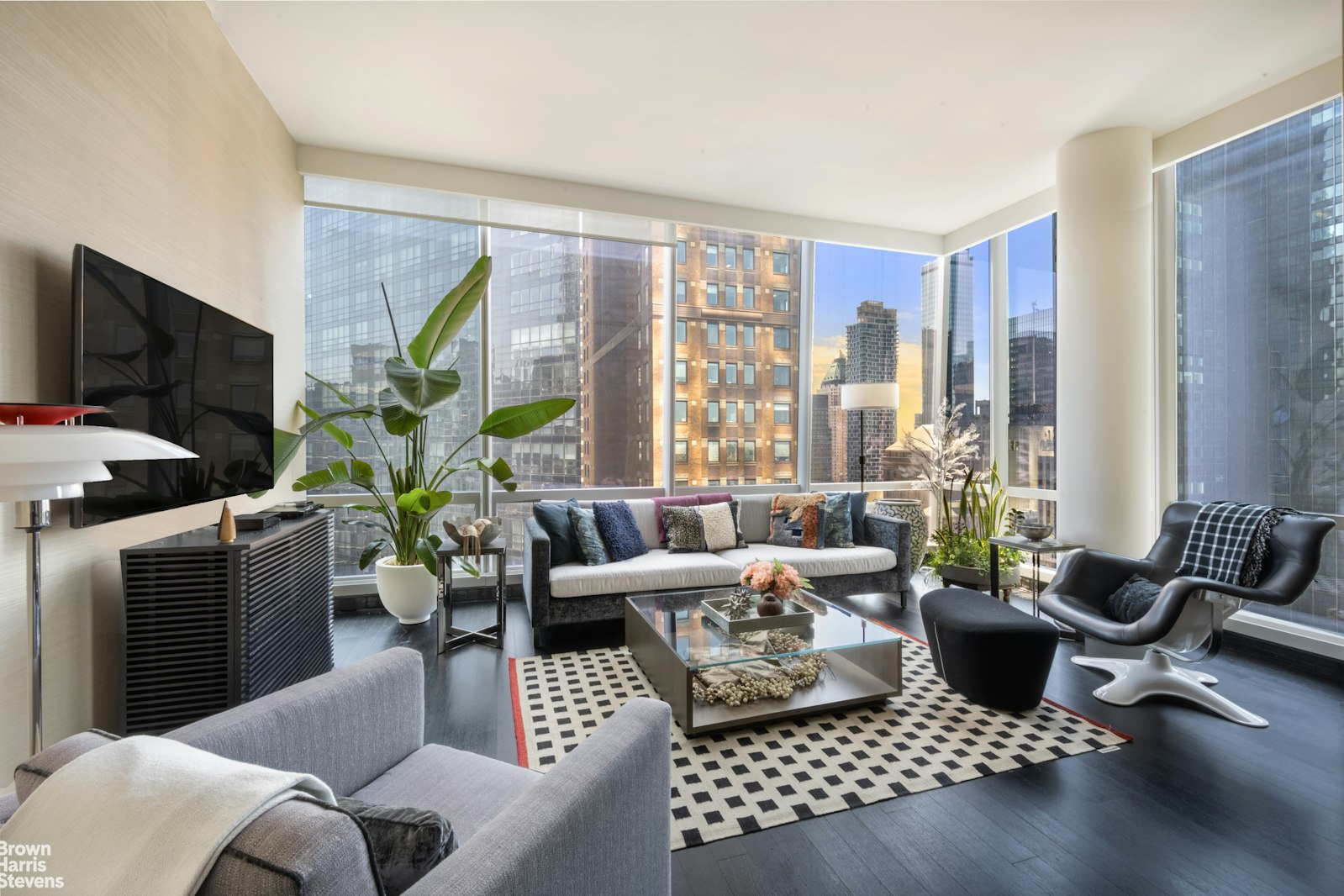 a living room with furniture floor to ceiling window and a flat screen tv