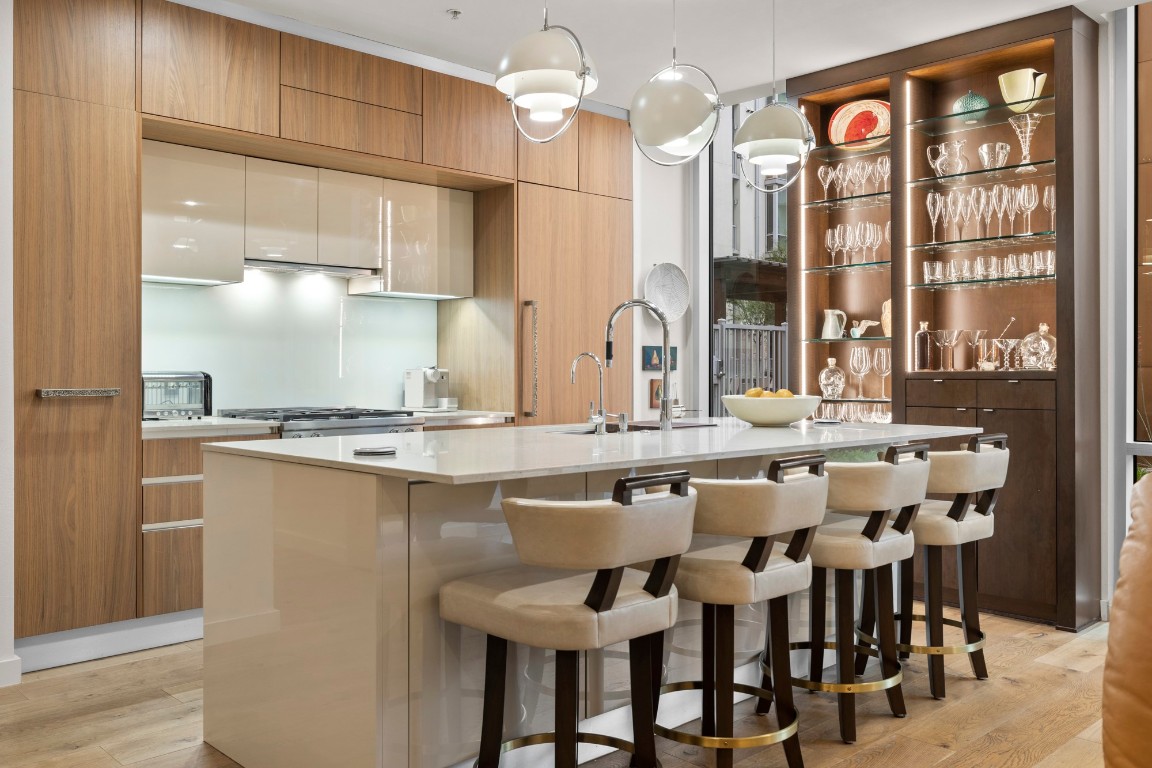 Gourmet kitchen with sleek walnut and lacquer Italian-made cabinets, quartz countertops and an massive expanded island with added storage