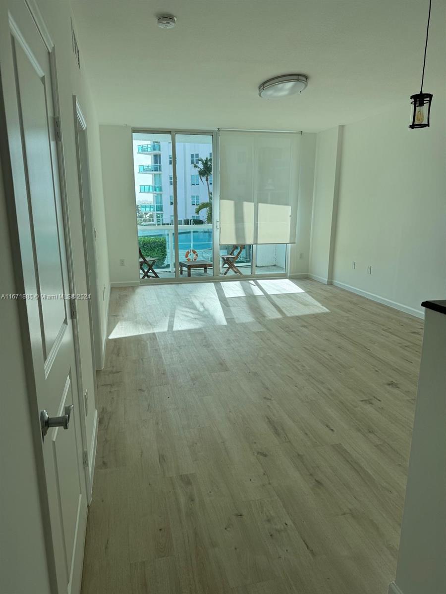 a view of a livingroom with wooden floor and a bathroom