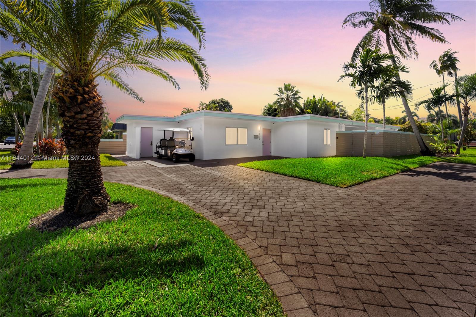 a front view of a house with a yard and palm trees