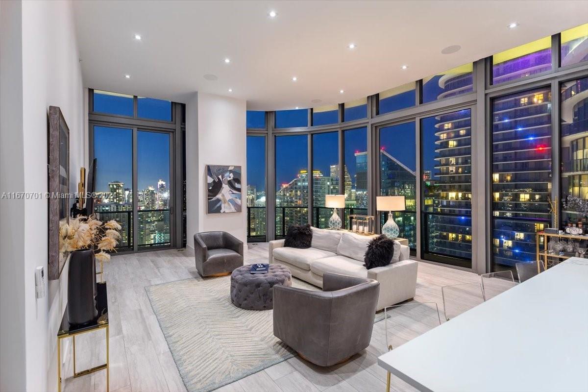 a living room with furniture a flat screen tv and floor to ceiling window