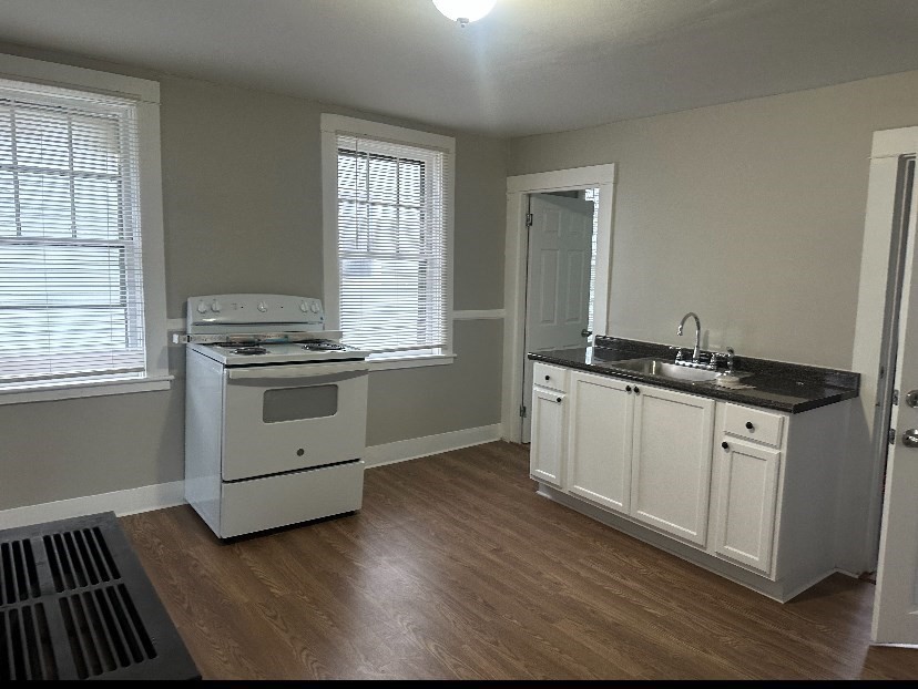 a kitchen with granite countertop a stove a sink and dishwasher with wooden floor