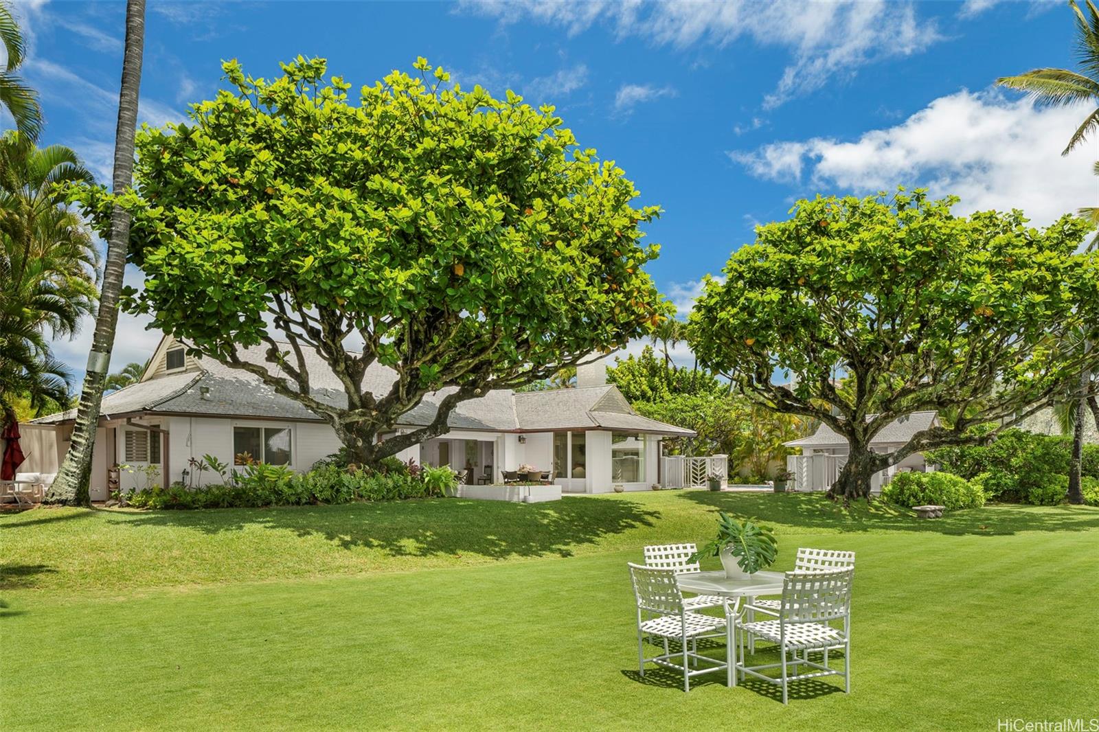 a white house with a big yard and large trees