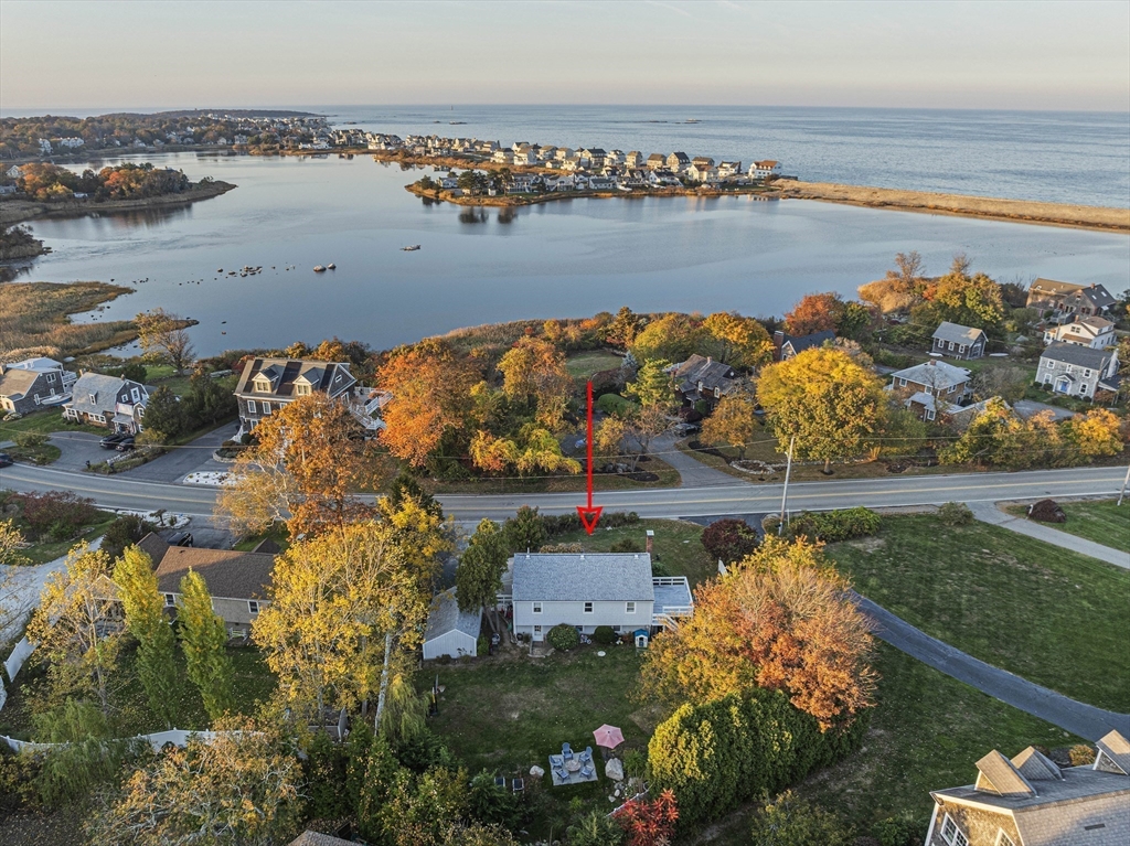 an aerial view of ocean and residential houses with outdoor space