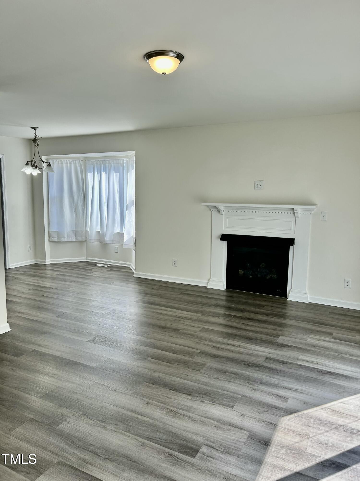 a view of empty room with wooden floor and fireplace