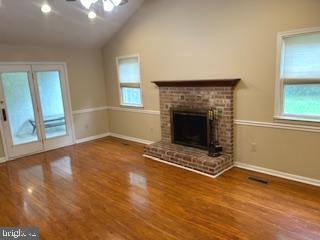 an empty room with wooden floor fireplace and windows