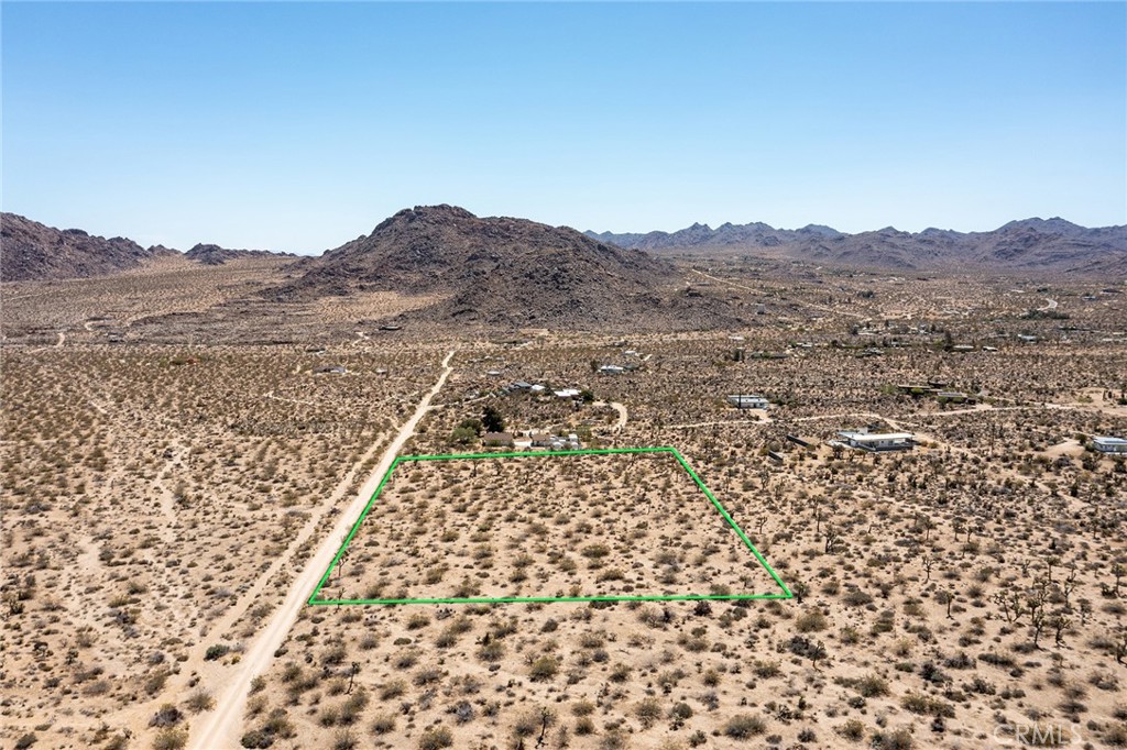 an aerial view of house with yard and mountain view in back